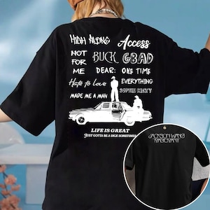 May include: Black oversized t-shirt with white text and graphics. The back of the shirt features phrases like "High Alone Access" and "Life is Great." A smaller image on the front shows "Jackson Wang Magic Man."
