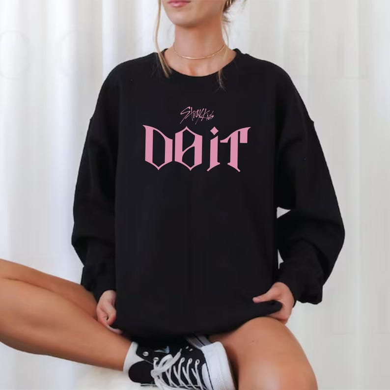 May include: Black sweatshirt with the pink text "Do It" in a gothic font. Above the text is the name "Stray Kids". The sweatshirt is worn by a person.