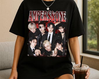 May include: Black t-shirt with a graphic of seven people and the text "AMPERS&ONE" in red and white. The image has a vintage style. The people are wearing dark clothing, creating a striking contrast.