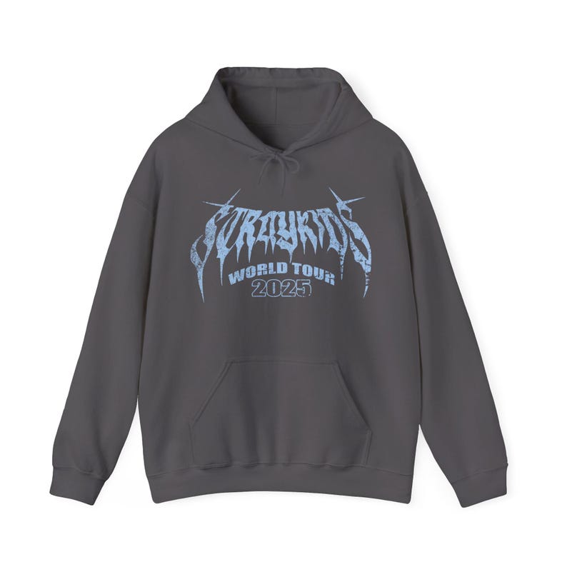 Puede incluir: Una sudadera con capucha gris oscuro con un bolsillo delantero y una capucha con cord&oacute;n. La parte delantera presenta el texto "Stray Kids World Tour 2025" en azul claro, con una fuente estilizada. La sudadera est&aacute; hecha de un material suave.
