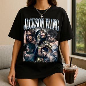 May include: Black t-shirt featuring a graphic of Jackson Wang with a distressed, vintage aesthetic. The design includes multiple images of Wang with a silver and blue text that reads "JACKSON WANG". The shirt is a crew neck and appears to be made of a soft material.