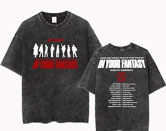May include: A black, acid-wash t-shirt featuring a white silhouette of figures and the words "ATEEZ" and "IN YOUR FANTASY" in red. The back of the shirt lists tour dates for the "ATEEZ 2025 WORLD TOUR IN YOUR FANTASY" in North America.