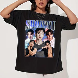 May include: Black t-shirt featuring a graphic of five men with the word "SHOWNU" in a silver and blue retro font. The graphic includes multiple images of the men in various poses. The shirt is a crew neck style.