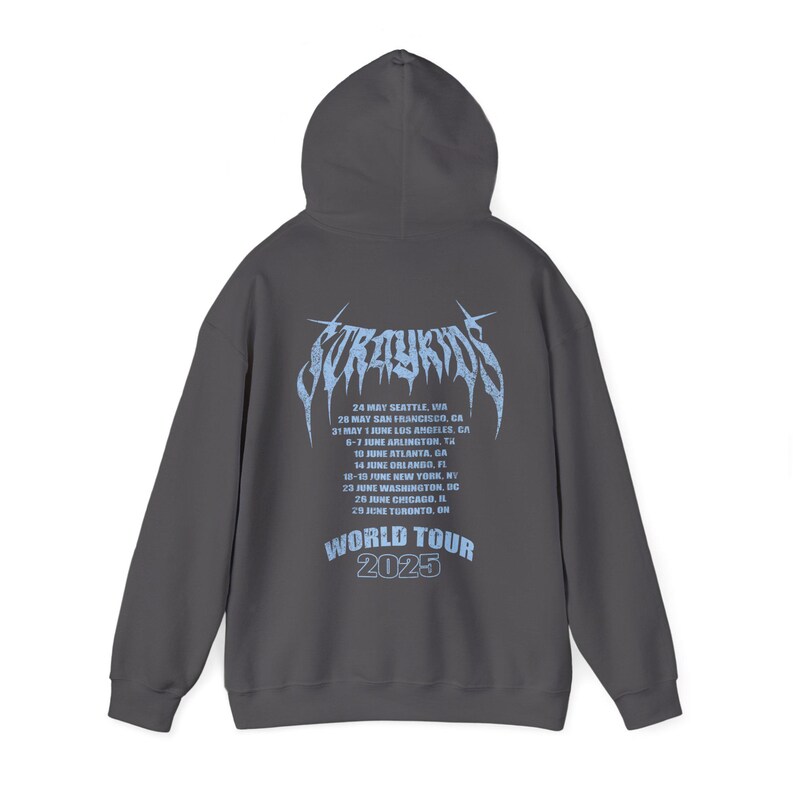 Puede incluir: Sudadera con capucha gris oscuro. La parte trasera presenta texto azul claro: "Stray Kids" en una fuente estilizada, una lista de fechas y lugares de la gira de 2025 y "World Tour 2025".