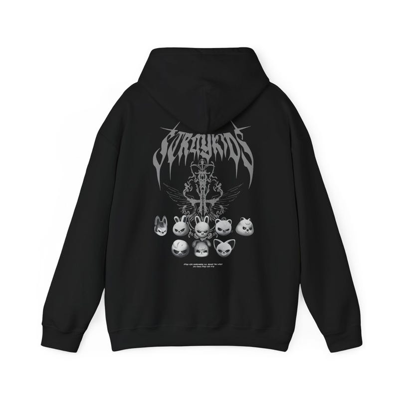 K&ouml;nnte beinhalten: Schwarzer Kapuzenpullover mit dem Text "Stray Kids" in einer gotischen Schriftart und einer Grafik von stilisierten Tiergesichtern in Grau und Wei&szlig;. Der Hoodie hat eine Kapuze und eine Vordertasche.