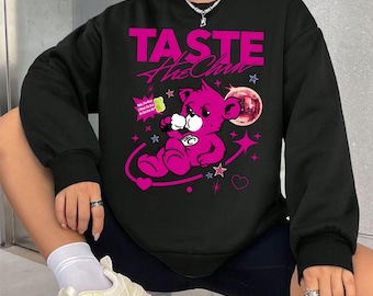 Puede incluir: Sudadera negra con un gráfico de un oso de peluche rosa, estrellas y el texto "TASTE The Chan". El oso sostiene una bebida y está rodeado de corazones y estrellas. El diseño es en tonos rosa y blanco.