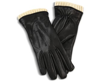 May include: A pair of black leather gloves with a ribbed, cream-colored knit cuff. The gloves are made of smooth leather and have a classic design. The gloves are likely for cold weather and are suitable for everyday wear.