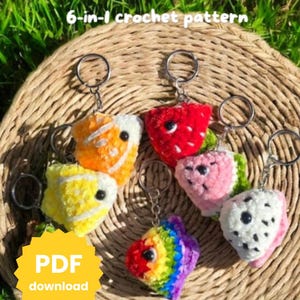 May include: Six crochet keyrings in the shape of fruit and fish. The keyrings are in various colours, including yellow, orange, red, pink, white, and rainbow. The text "Fruit Fish" and "6-in-1 crochet pattern" are at the top. The text "PDF download" is in a yellow starburst.