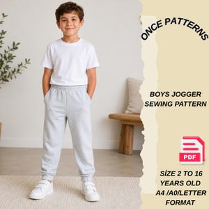 May include: A young boy wearing a white t-shirt and gray sweatpants stands in front of a neutral background. The image includes text that reads "ONCE PATTERNS" and "BOYS JOGGER SEWING PATTERN". The text also indicates the pattern is for sizes 2 to 16 years old.