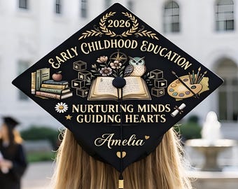 May include: Black graduation cap decorated with gold text and illustrations. The cap reads "Early Childhood Education" and "Nurturing Minds Guiding Hearts." A name, "Amelia," is featured below the text. The cap has a black tassel.