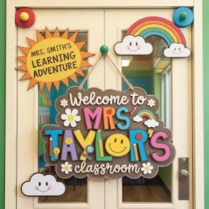 May include: A wooden classroom sign with the text "Welcome to MRS TAYLOR'S classroom" in colorful letters, decorated with flowers, a smiley face, and a rainbow. Additional signs include a sun with "MRS. SMITH'S LEARNING ADVENTURE" and a rainbow with clouds.