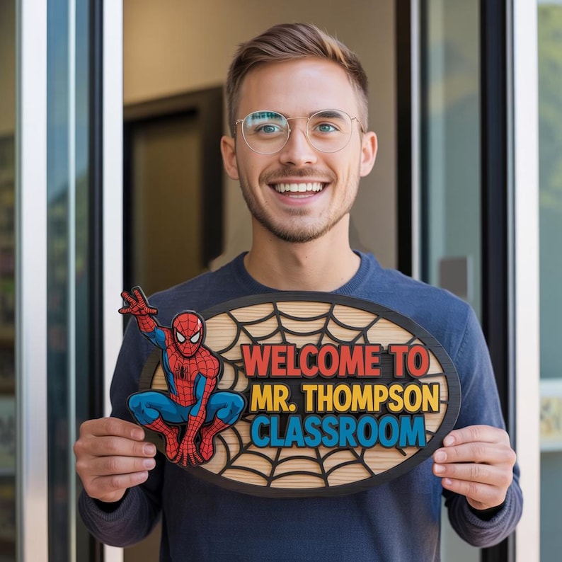May include: An oval wooden sign with a Spider-Man graphic and the text "WELCOME TO MR. THOMPSON CLASSROOM." The sign has a black border and a light brown background with a spiderweb design. The Spider-Man figure is in red, blue, and black.