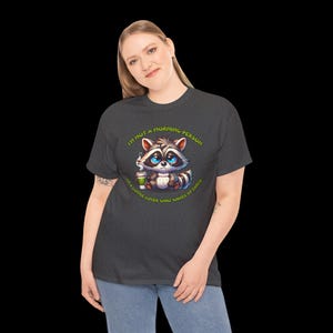 May include: A dark gray t-shirt with a cartoon raccoon holding a cup of coffee. The text on the shirt reads "I'm not a morning person, I'm a coffee lover who wakes up early."
