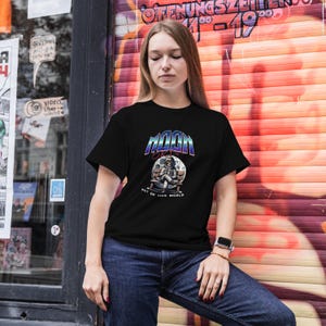 May include: Black t-shirt with a graphic of an astronaut sitting on the moon. The graphic has the text "MOON" and "OUT OF THIS WORLD".