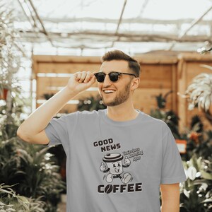May include: A light gray t-shirt with a coffee-themed graphic. The graphic features a cartoon coffee cup with the words "GOOD NEWS" above and "COFFEE" below. The text "You're Less Annoying After" is also included.