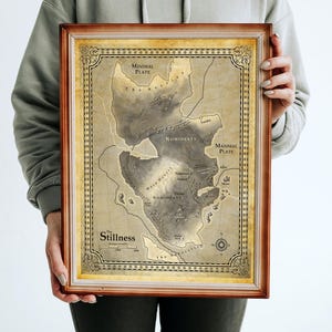 May include: A framed map print with a vintage aesthetic. The map features landmasses labeled "Minimal Plate," "Nomidlats," and "Somidlats." The title "Stillness" is at the bottom. The frame is a warm brown.