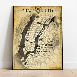 May include: Framed map of New York City with a vintage aesthetic. The map features key locations with icons and text, including "Hotel Dumort" and "City of Bones." The words "New York City" are at the top. The map is on a wooden floor.