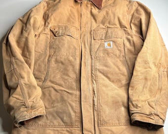 Peut inclure: Veste de travail beige avec un col en velours côtelé marron. La veste comporte deux poches de poitrine, deux poches inférieures et un écusson logo Carhartt. La veste est faite d'un matériau durable et robuste.