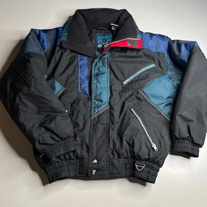 May include: A black and teal vintage winter jacket with a high collar, red accents, and zippered pockets. The jacket features blue and teal panels and a black ribbed hem and cuffs. A retro style winter coat.