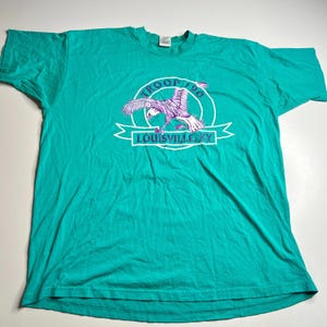 May include: Teal-colored t-shirt featuring a graphic with an eagle and the text "TROOP 190 LOUISVILLE KY" in white and purple. The shirt is made of a soft material and has short sleeves.