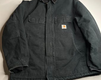 Puede incluir: Chaqueta de trabajo negra con cuello de pana marrón. La chaqueta tiene dos bolsillos en el pecho y un pequeño parche con el logotipo en la parte delantera. Fabricada con material resistente.