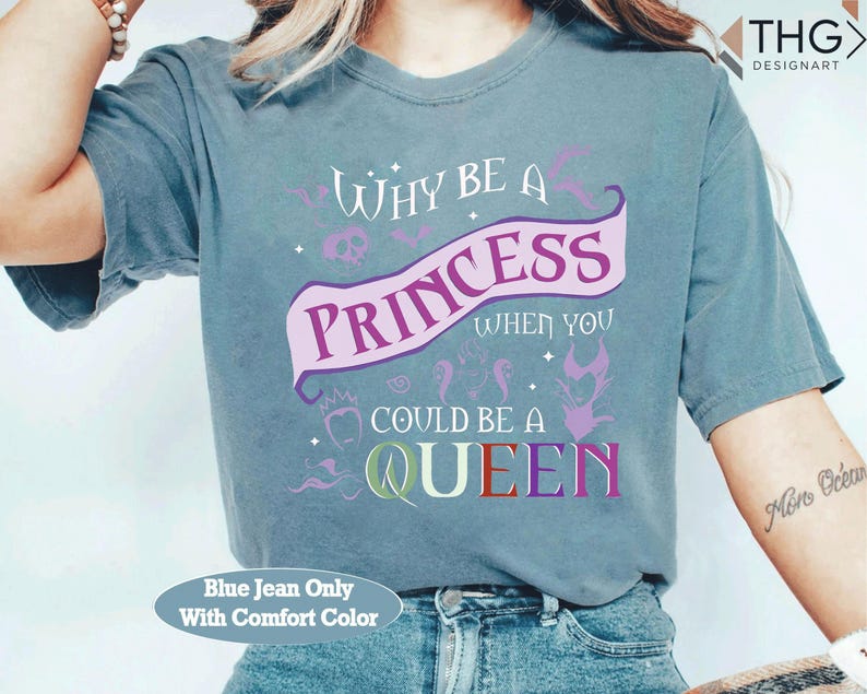 May include: Blue jean comfort color t-shirt with the text "WHY BE A PRINCESS WHEN YOU COULD BE A QUEEN" in purple, pink, and green. The design includes a banner, skull, and other decorative elements.