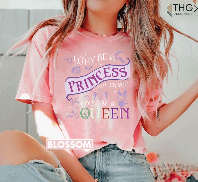 May include: Pink t-shirt with the text "Why be a Princess when you could be a Queen" in purple and white. The shirt has a crew neck and short sleeves. The word "Blossom" is printed on the bottom left.