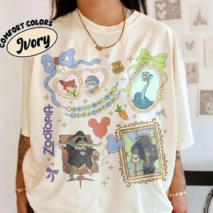 Puede incluir: Camiseta de color marfil con personajes y gr&aacute;ficos de Zootopia. El dise&ntilde;o incluye retratos enmarcados, gafas de sol en forma de coraz&oacute;n con personajes y el texto "Welcome to Zootopia". La camiseta tiene un corte holgado.