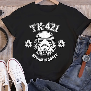 May include: A white ceramic mug with a black handle and the text "But First, Coffee" in a black, bold font. The mug is on a white surface.