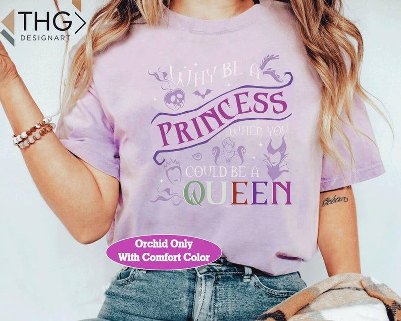 May include: A light purple t-shirt with the text "WHY BE A PRINCESS WHEN YOU COULD BE A QUEEN" in purple, green, and red. The shirt has a crew neck and short sleeves. The text "Orchid Only With Comfort Color" is also visible.