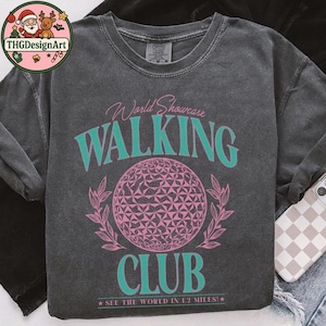 May include: Dark gray sweatshirt with a pink and teal graphic. The graphic reads "World Showcase Walking Club" with a geometric sphere design and the text "See the world in 1.2 miles!"