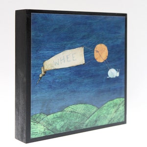 May include: A wooden framed art print with a blue background and a white banner that says "WHEE" being pulled by a snail with a red sun in the background.