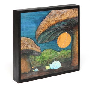 May include: A framed painting of a whimsical scene with two snails under a large mushroom. The snail in the foreground is pulling a string attached to a bright orange circle. The background is a blue sky with a green landscape.