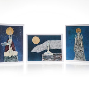May include: Three art prints featuring a blue background with a gold moon and a figure in white. The first print shows a figure with arms raised, the second print shows a figure with a white cloth behind them, and the third print shows a figure with arms raised in a prayer-like pose.