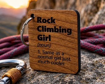May include: A square wooden keychain with a dark brown finish featuring black engraved text that reads: Rock Climbing Girl (noun) 1. Same as a normal girl just much cooler. The keychain includes a silver metal split ring attached to the top corner.