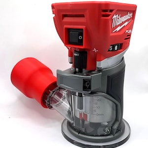 Puede incluir: Una fresadora Milwaukee FUEL roja y negra con base de plástico transparente. La fresadora tiene un interruptor de encendido, un dial con números y un accesorio rojo para la recolección de polvo. Herramienta para carpintería.