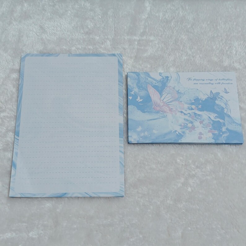 May include: A blue and white stationery set with a butterfly design. The envelope features a butterfly with the text "The flapping wings of butterflies are resonating with freedom".
