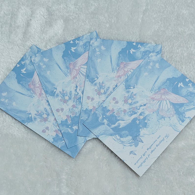 May include: Four blue and white cards with a watercolor design of butterflies and flowers. The text on the card reads "The true colors of happiness are smiles and laughter".