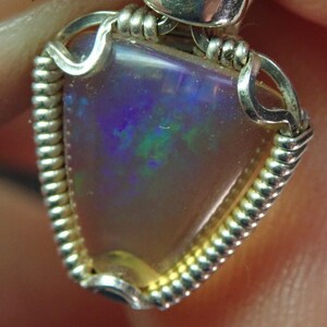 May include: A silver wire wrapped pendant featuring a triangular opal with iridescent blue, green, and purple hues.