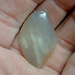 May include: A smooth, white agate stone with a translucent, cloudy appearance. The stone has a natural, irregular shape.