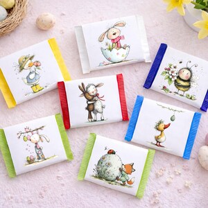 May include: Assortment of Easter-themed chocolate bars with colorful wrappers. Each bar features a different whimsical illustration of animals like bunnies, ducks, and bees. Decorative Easter eggs and a nest are scattered around the bars.
