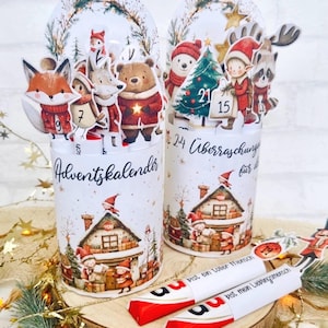 Könnte beinhalten: Zwei weiße Adventskalender mit festlichen Illustrationen von Waldtieren und einem Weihnachtsdorf. Jeder Kalender hat einen dekorativen Kranz und eine Zahl oben. Der Text "Adventskalender" ist sichtbar.