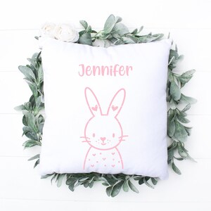 May include: White pillow with pink bunny illustration and the name Jennifer printed on it.