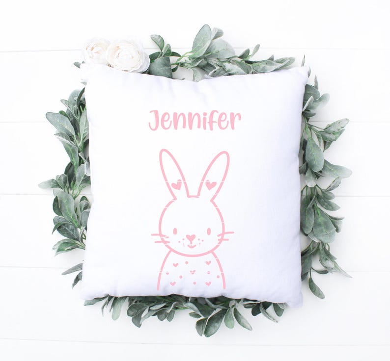 May include: White pillow with pink bunny illustration and the name Jennifer printed on it.