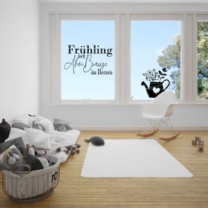 May include: A window decal with the text "Fr&uuml;hling ist  Ahoi Brause im Herzen" and a silhouette of a watering can with flowers. The decal is on a window in a room with a white rocking chair and a white rug.