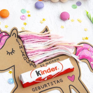 May include: A brown cardboard unicorn with pink glitter and a pink, white, and peach yarn mane. The unicorn has a Kinder chocolate bar attached to it and the text "Einladung zu meinem Geburtstag".