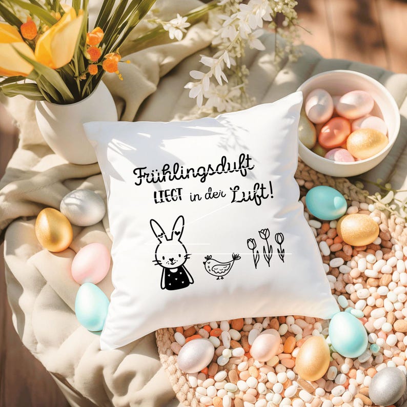 May include: White pillow with black text that reads "Fr&uuml;hlingsduft liegt in der Luft!" and a black and white illustration of a bunny, a bird, and flowers.