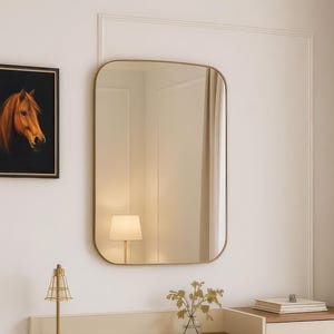 Può includere: Un moderno set da toeletta con specchio rettangolare, scrivania con cassetto e mobile a tre cassetti. La scrivania ha piano e gambe in legno e uno sgabello abbinato. Un ritratto di cavallo incorniciato è appeso al muro.