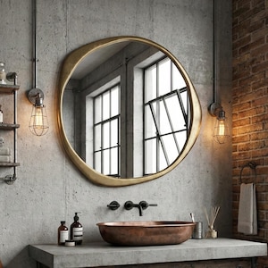 May include: An industrial-style bathroom featuring a round gold mirror above a concrete countertop with a copper sink. The vanity is made of wood and metal. A brick wall and a woven rug add to the aesthetic. The room has a modern, minimalist feel.