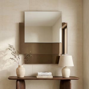 May include: A contemporary hallway scene with a dark wood console table and a square mirror. A cream lamp and vase with foliage are on the table. The walls are a light beige, creating a minimalist design. The table is approximately 120 cm long.